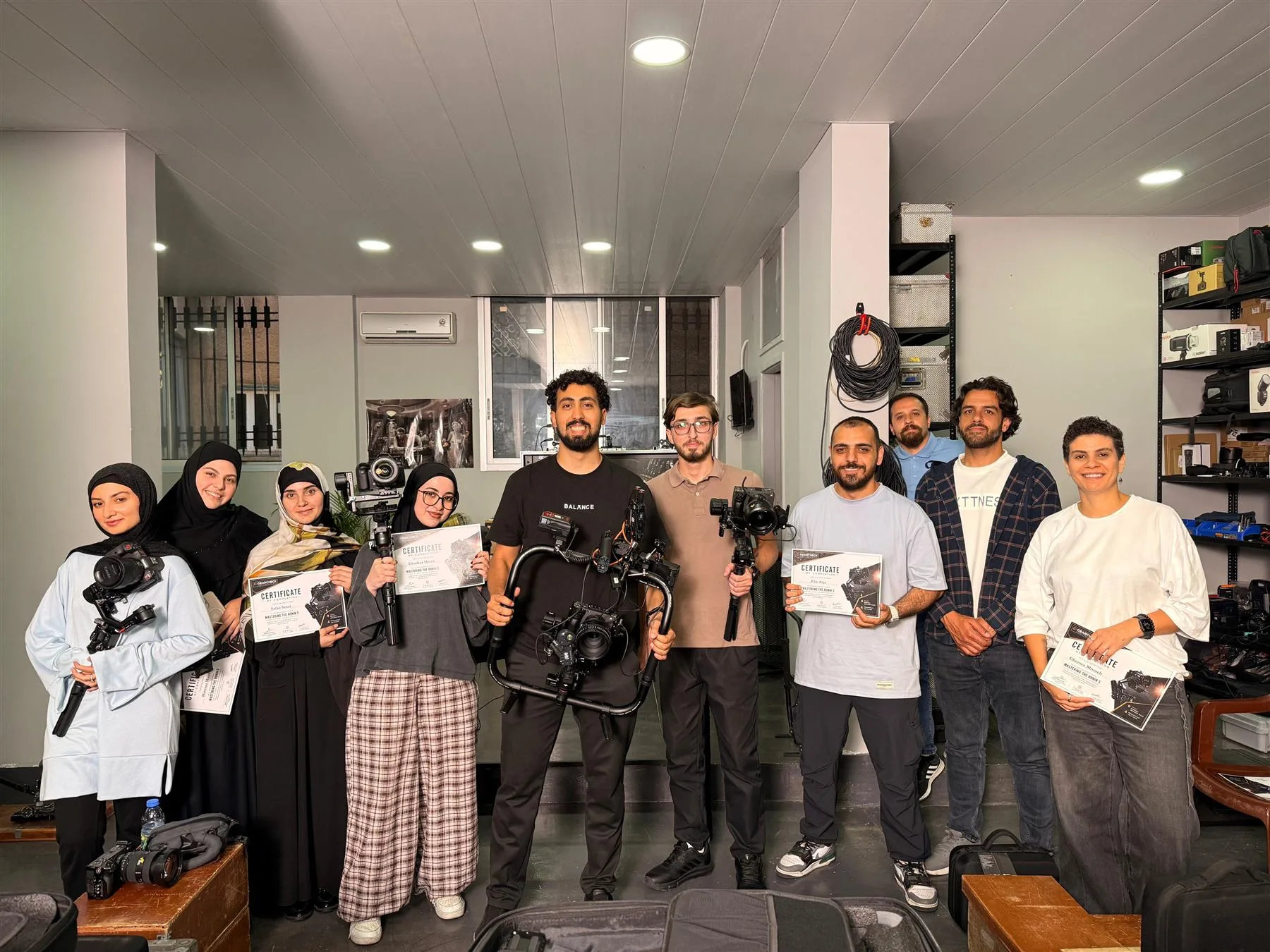 Mohammad instructing a Ronin workshop, participants holding gimbals and completion certificates